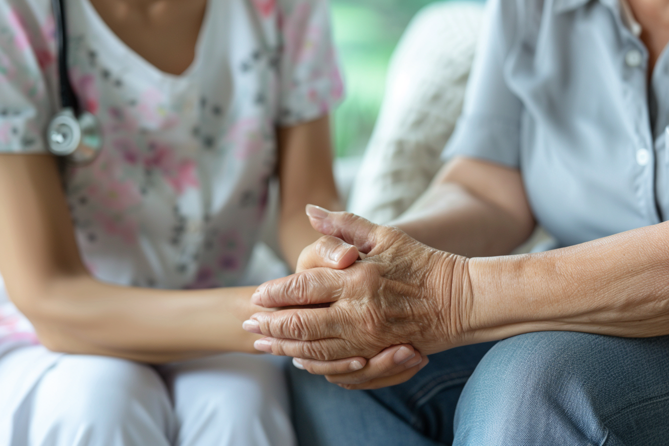 A senior sitting with a nurse and discussing her situation as the nurse comforts her.