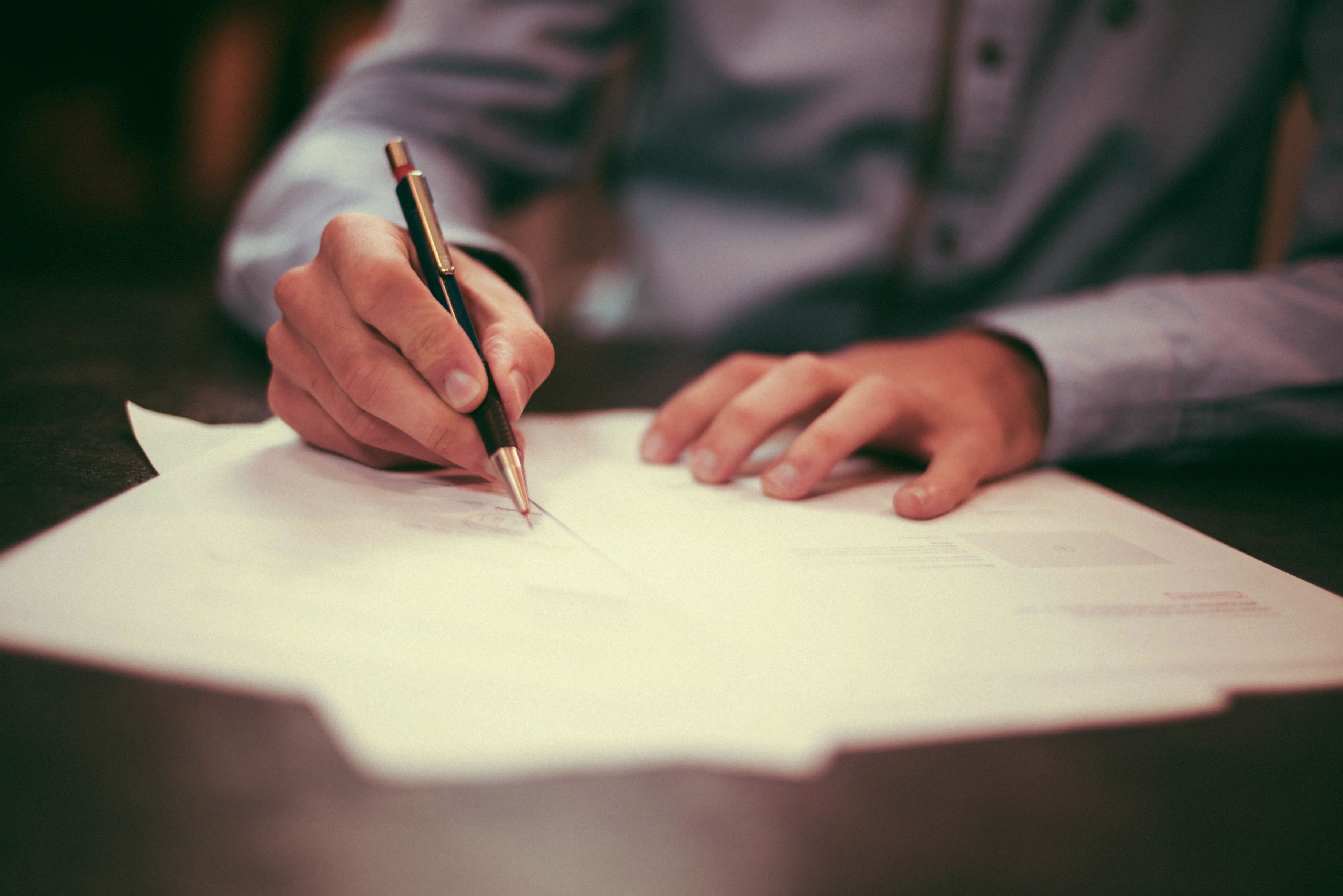 A person holding a pen and reviewing documents.